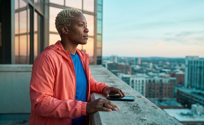 Person looking toward dawn from an apartment balcony after reviewing payment options.