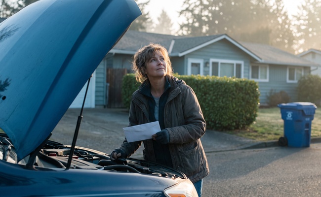 A woman holds an unopened envelope in her driveway while deciding what to do with unexpected money.