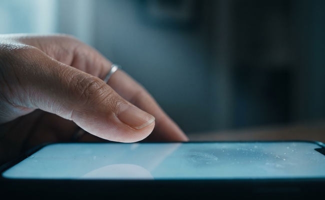 Close view of a thumb hesitating above a phone screen before replying to a collector.