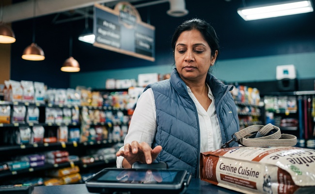 Shopper hesitating above a card reader before agreeing to pay an added collection charge.