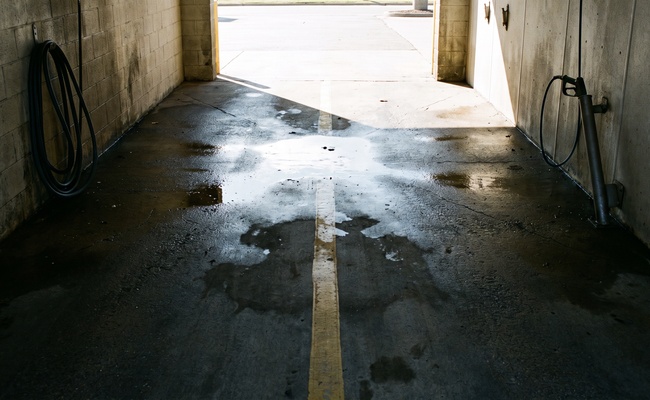 An empty coin-operated car wash bay standing idle, illustrating income that stops moving when a bank account is frozen after judgment.