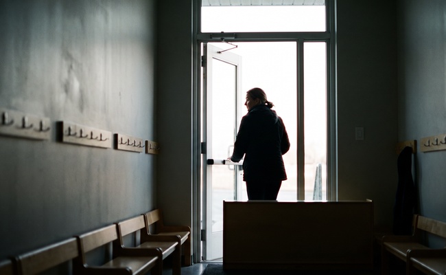 A parent leaving a daycare doorway in early morning light, carrying the daily costs that continue during a bank account frozen after judgment.