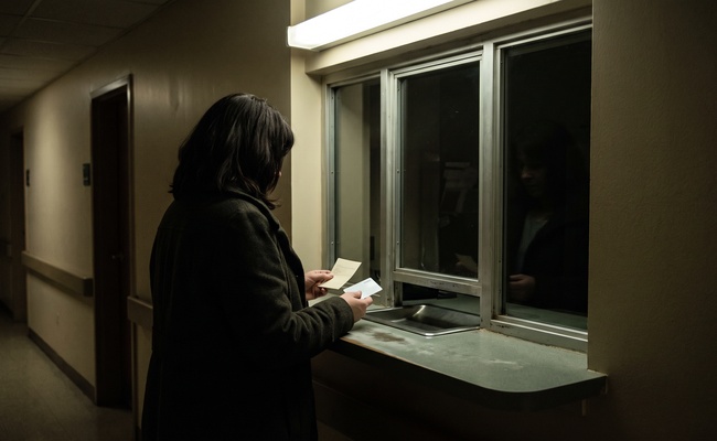 A woman at a night registrar window after a card declined because a creditor moved to take money from a joint account.