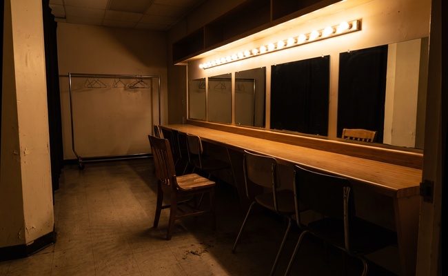 An empty dressing room with one chair pulled out, the quiet before testimony at a judgment debtor examination begins.