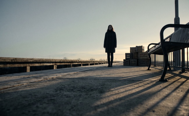 Empty railway platform at first light with a solitary figure looking down the track after her file is clear