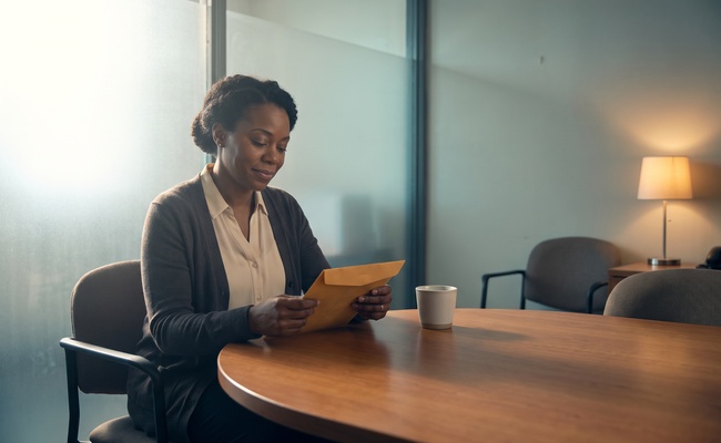 Person holds a closed confirmation envelope in a quiet consultation room after an account-removal request.
