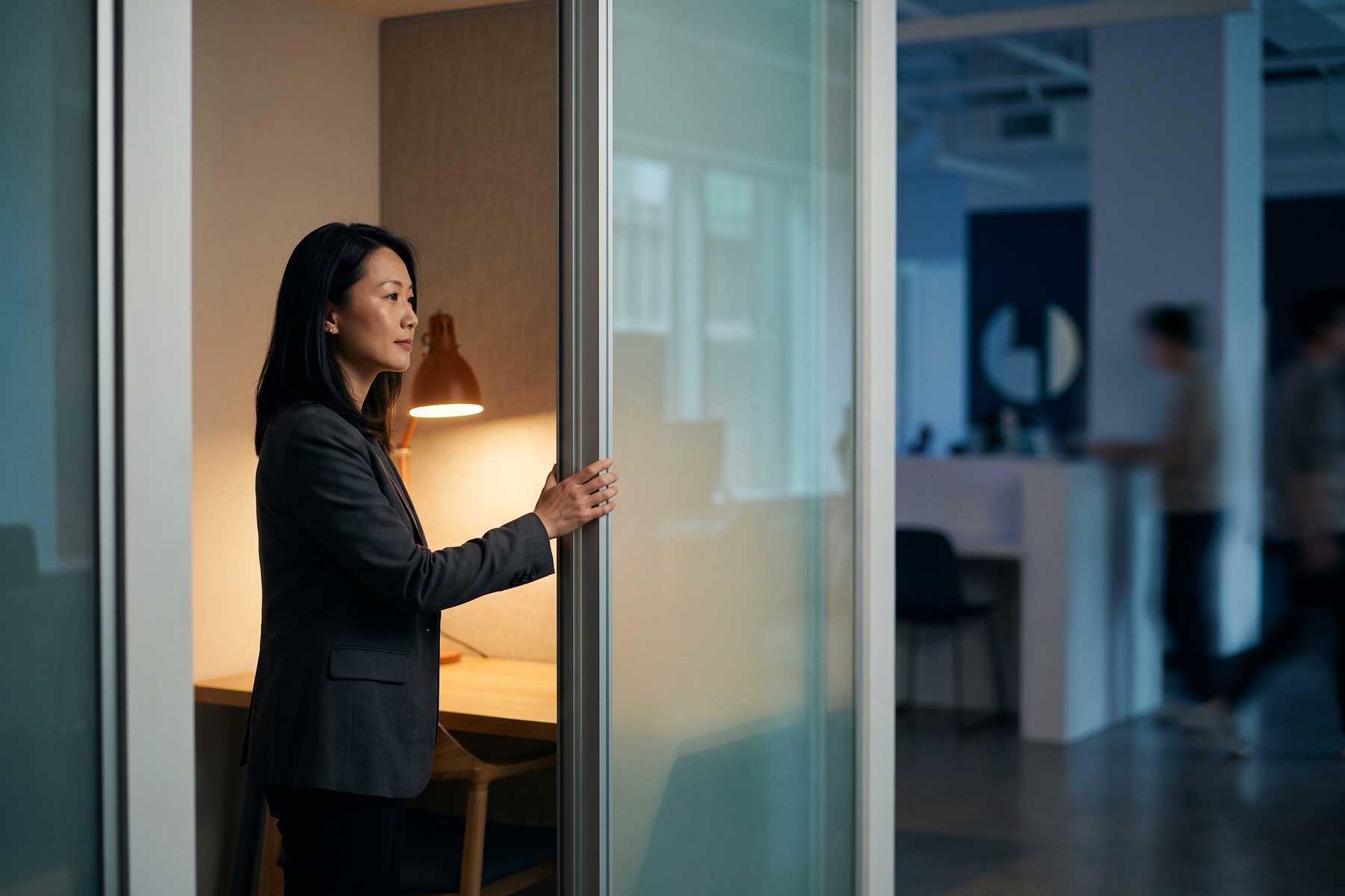 An adult calmly closes a translucent acoustic divider to create a quiet personal workspace.